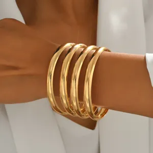 Gros bracelets jonc en métal doré empilés, design géométrique rond minimaliste pour femmes.