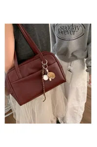 Detail view of large capacity dark red leather shoulder tote bag with cute baseball charm.
