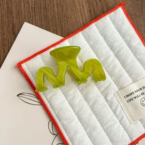 Green wavy acetate hair claw detail shot, elegant translucent zigzag hair clip accessory.
