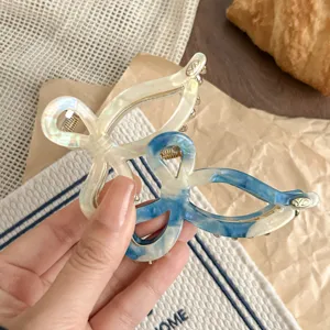 Detailed view of elegant acetate bow hair claw clips in white and blue marbled design.