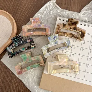 Detailed view of small acetate hair claws in assorted vintage patterns with gold metal accents.