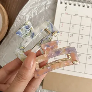Close-up detail of retro acetate hair claw clips in marble oil painting style with gold edge.