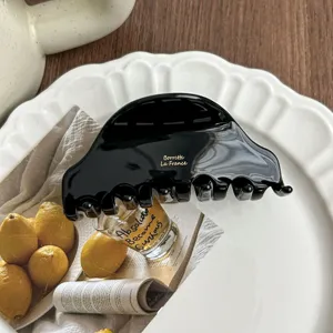 Detailed shot of a black acetate hair claw clip, elegant French style fashion hair accessory.