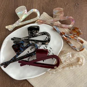Detailed view of trendy acetate hair claws, large fish tail design, elegant retro hair accessories.