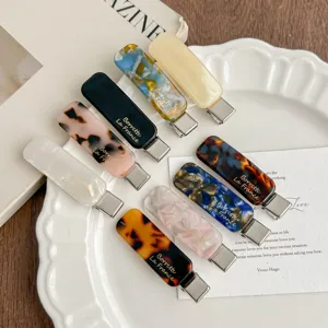 Detailed flat lay shot of trendy Korean style acetate tortoiseshell hair clips on white plate.