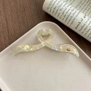 Close-up detail shot of the irregular iridescent acetate large hair claw clip on white tray.