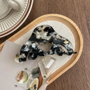 Detail view of the acetate hair claw clip featuring chic heart cutout and elegant pattern.