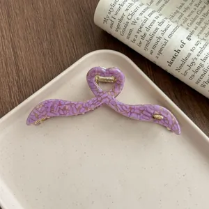 Detailed close-up of a purple acetate hair claw clip with unique heart shape and irregular wings.