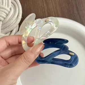 Close-up detail of irregular hair claw clips in iridescent white and dark blue for women.