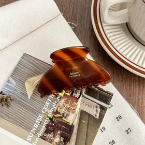 Tortoiseshell acetate hair claw clip detail shot, stylish brown medium shark clip accessory.
