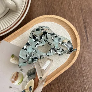 Acetate hair claw clip detail, minimalist black and white marble pattern aesthetic hair accessory.