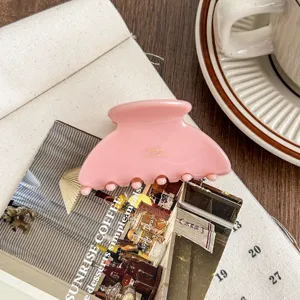 Detailed close-up of a stylish pink acetate hair claw clip showcasing elegant texture and design.