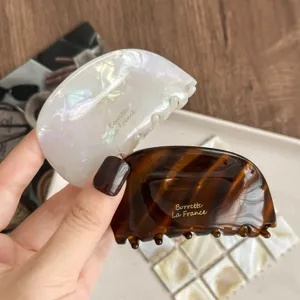 Detaillierte Acetat Haarklammern in elegantem Weiß und Schildpatt für schicke Hochsteckfrisuren.