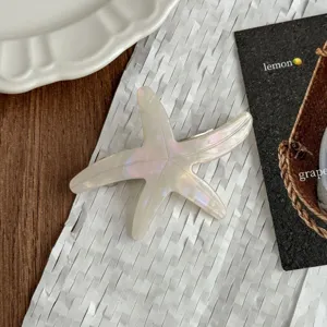 Detail shot of white pearlescent starfish hair clip, glossy acetate material accessory.