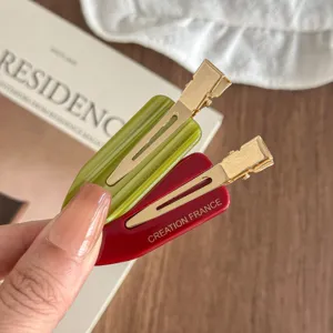 Detailed shot of acetate hair clips in green and red colors with metal duckbill clips.