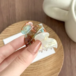 Close-up detail of small acetate hair claw clip, featuring leopard print and mother-of-pearl.