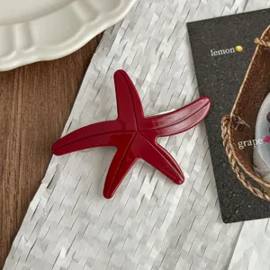 Detailed view of the red acetate starfish hair clip, showcasing glossy surface and spring clasp.