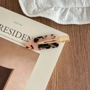 Detail shot of exquisite acetate hair clip with tortoise shell pattern and gold metal clasp.