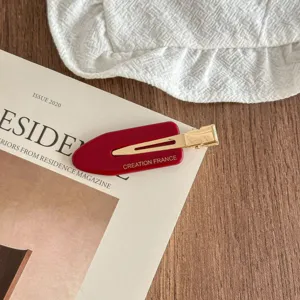 Red acetate duckbill hair clip featuring gold metal interior, stylish side hairpin detail.