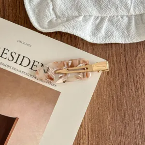 Detailed view of fashionable tortoiseshell acetate hair clip with a sleek gold metal snap design.