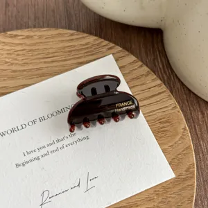 Detailed close-up view of a small dark brown hair claw clip featuring exquisite handmade finish.