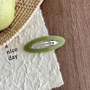Detailed close-up of green acetate oval hollow hair clip, showcasing exquisite texture and design.