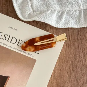 Detailed closeup of a stylish tortoise shell acetate hair clip with gold metal duckbill clip.