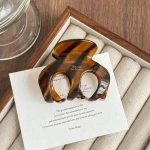 Detailed close-up of the elegant brown tortoiseshell hair claw clip displayed on a tray.