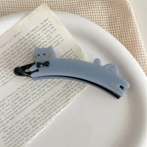 Detailed close-up shot of a cute blue cat banana hair clip with black bow and gold text.