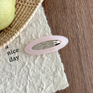 Pink oval acetate hair clip detail shot, featuring hollow design and metal snap clip closure.