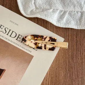 Tortoiseshell acetate hair clip with gold metal snap detail, elegant side bang accessory.