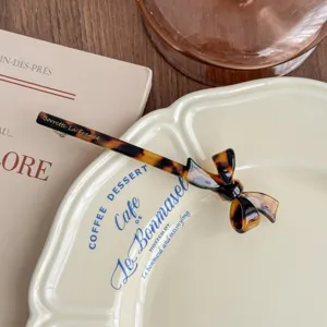 Detailed shot of Korean style tortoise shell acetate bow hair clip, elegant retro flat lay.