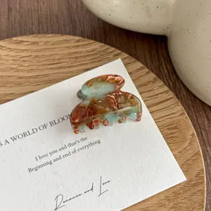 Small acetate hair claw clip with stylish tortoise shell pattern, elegant detail view.