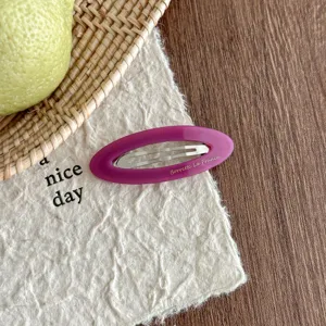 Detailed view of purple oval acetate hair clip with hollow design, elegant styling accessory.