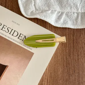 Detailed shot of green acetate hair clip with gold metal snap, stylish side bobby pin style.