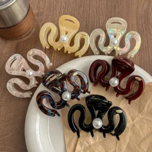 Detailed view of trendy resin hair claws with pearl and metallic accents, chic hair accessories.
