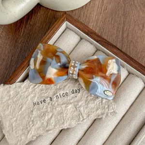 Detail shot of French style rhinestone bow hair clip, acetate material with elegant finish.