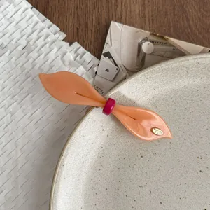 Close-up detail of the orange willow leaf spring hair clip with a chic pink bow ring.