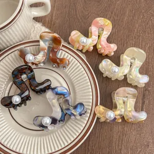 Close-up detail of stylish acetate hair claw clips with faux pearls, elegant hair accessories.
