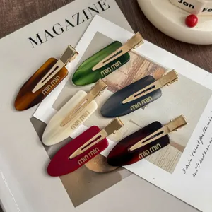 Detailed view of colorful acetate hair clips, duckbill design with gold metal and chic style for women.