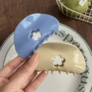 Detail view of cute floral hollow hair claw clips in charming blue and beige colors for daily wear.