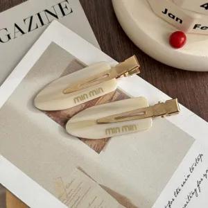 Close-up of elegant beige acetate hair clips with metal clips, chic fashion accessories.