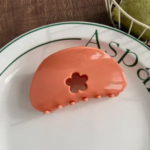 Peach orange hair claw clip with floral cutout detail, elegant acetate shark hair accessory detail.