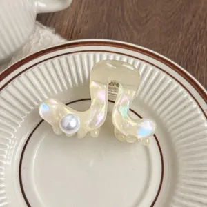 Close-up detail of the iridescent acetate hair claw featuring a pearl on ceramic plate.