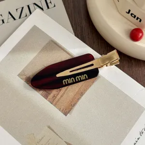 Detailed view of the elegant tortoiseshell acetate hair clip with golden min min letters.