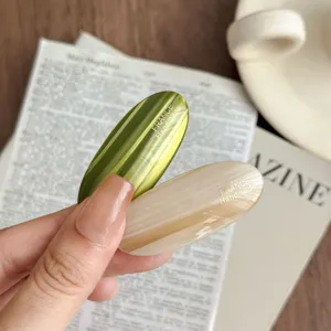 Acetate oval hair clip detail view, featuring elegant green and beige barrette design.