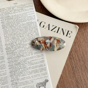 Acetate oval hair clip detailed shot showcasing delicate tortoiseshell pattern and golden text.