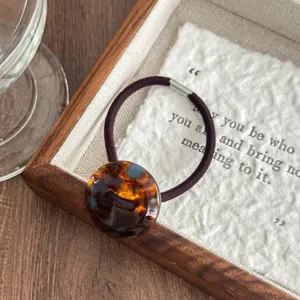 Detailed close-up shot of the vintage tortoiseshell acetate button hair tie texture and elastic band.