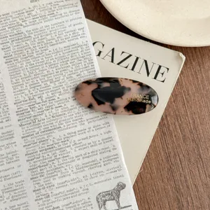 Detailed view of an elegant oval acetate hair clip with classic tortoiseshell pattern design.
