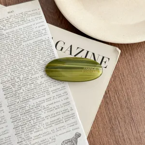 Detail shot of elegant oval green acetate hair clip with exquisite handmade craftsmanship.